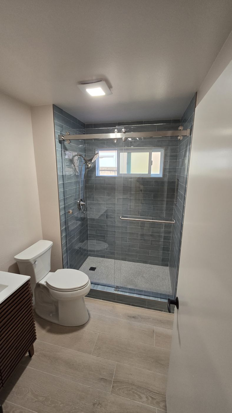 Shower with blue plank tile, sliding glass door and window